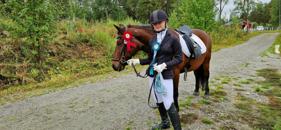 Astrid viser stolt frem hesten sin, Åse Rosa, med premiene.
 Foto: Hill Haga