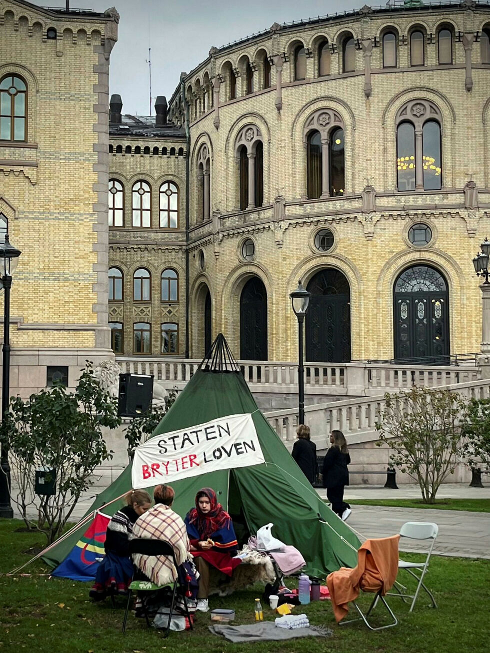 Ella Marie Hætta Isaksen og Ida Helene Benonisen besøker Mihkkal Hætta som campet med lavvo foran Stortinget – i protest mot at staten ikke reagerte på høyesterettsdommen i Fosen-saken fra oktober 2021.
 Foto: Tone H H Bull-Kjølaas