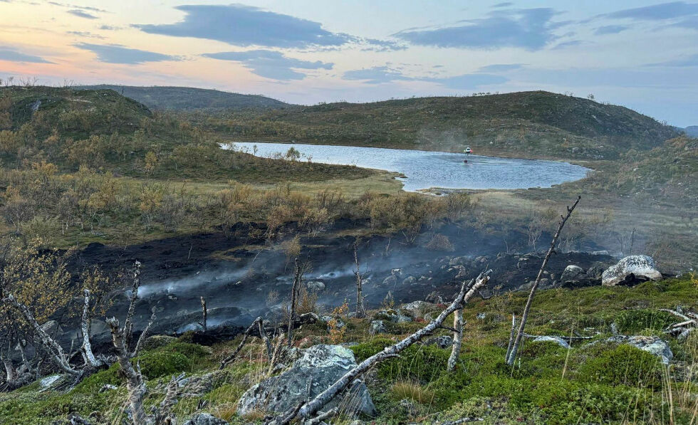 Med hjelp av helikopter (i bakgrunnen) fikk man slukket flammene da brannen oppsto ved Skitjern/Luoppalat mandag.
 Foto: Nesseby brannvesen